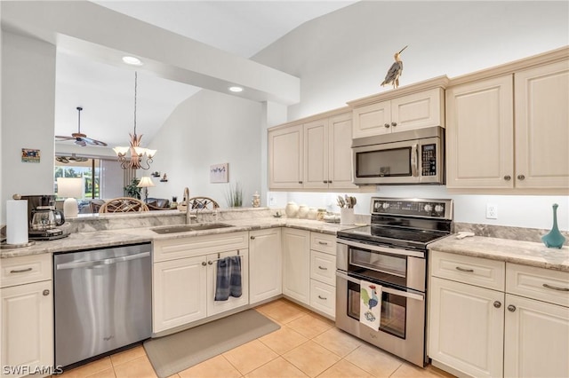 kitchen featuring lofted ceiling, sink, appliances with stainless steel finishes, light tile patterned floors, and cream cabinets