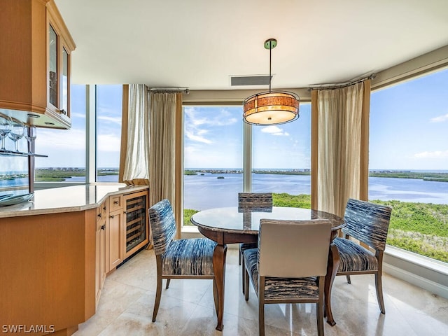 tiled dining room featuring a water view and beverage cooler