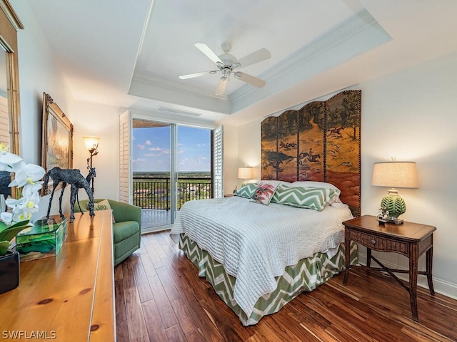 bedroom featuring dark hardwood / wood-style flooring, ornamental molding, access to outside, ceiling fan, and a tray ceiling