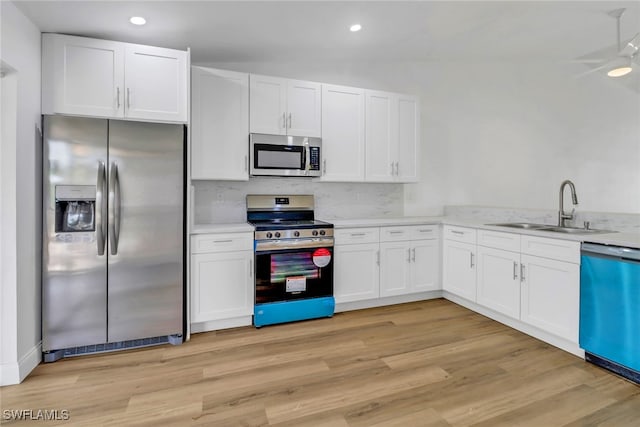 kitchen with white cabinetry, sink, light hardwood / wood-style floors, and appliances with stainless steel finishes