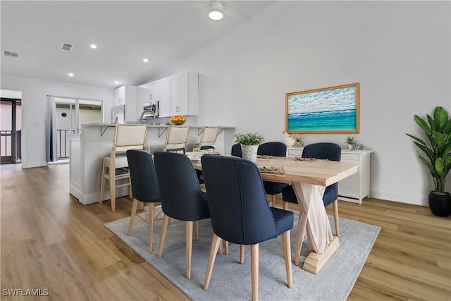 dining room featuring vaulted ceiling, light hardwood / wood-style flooring, and sink