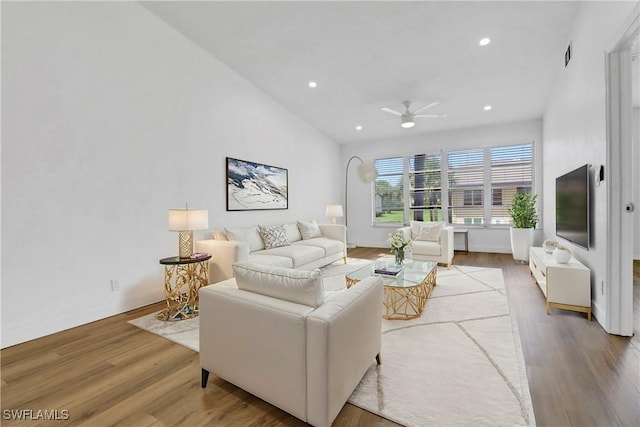 living room featuring ceiling fan, light hardwood / wood-style floors, and vaulted ceiling