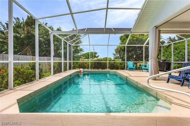 view of swimming pool featuring glass enclosure and a patio