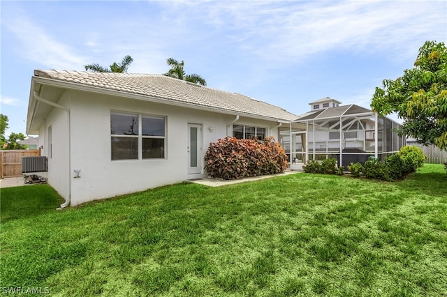 back of property with a lawn and a lanai