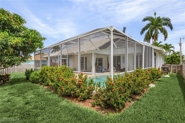 rear view of house featuring a yard, a fenced in pool, and glass enclosure