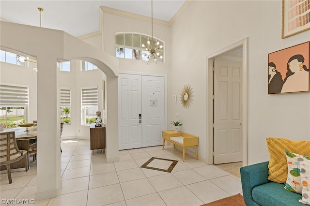 tiled entrance foyer featuring plenty of natural light, a towering ceiling, and ornamental molding