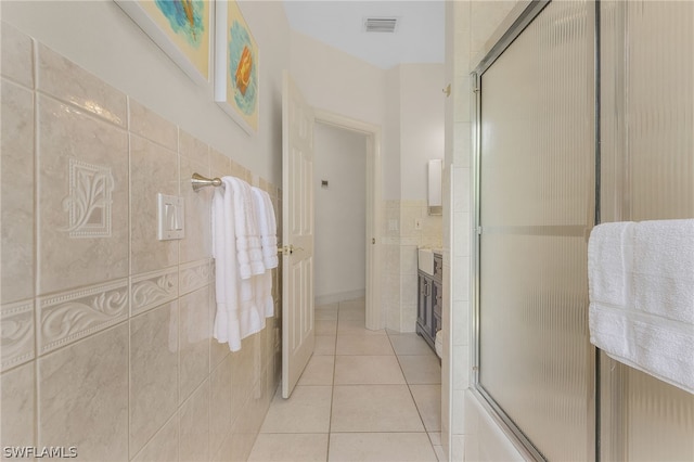 bathroom with shower / bath combination with glass door, vanity, tile patterned floors, and tile walls