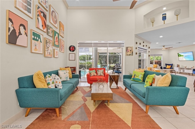 tiled living room with ceiling fan, a towering ceiling, and ornamental molding