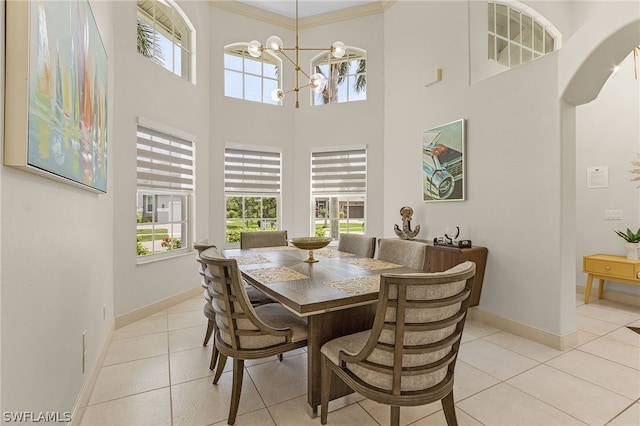 tiled dining room featuring a high ceiling, an inviting chandelier, and ornamental molding