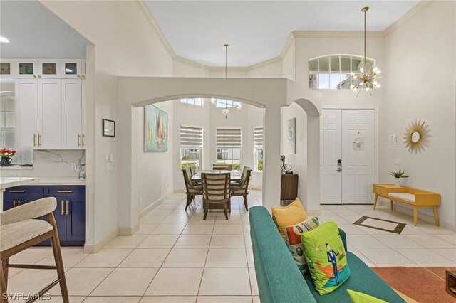 tiled foyer entrance featuring a notable chandelier and ornamental molding