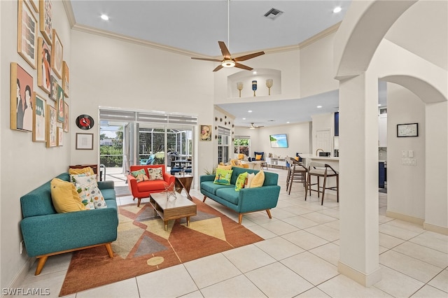 living room with ceiling fan, light tile patterned flooring, a high ceiling, and ornamental molding