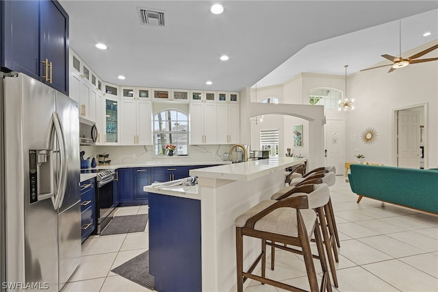 kitchen with tasteful backsplash, blue cabinets, a breakfast bar area, white cabinets, and appliances with stainless steel finishes