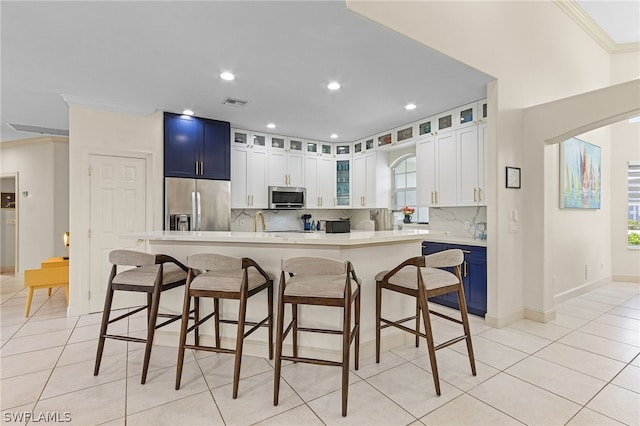 kitchen featuring stainless steel appliances, tasteful backsplash, blue cabinets, light tile patterned floors, and ornamental molding