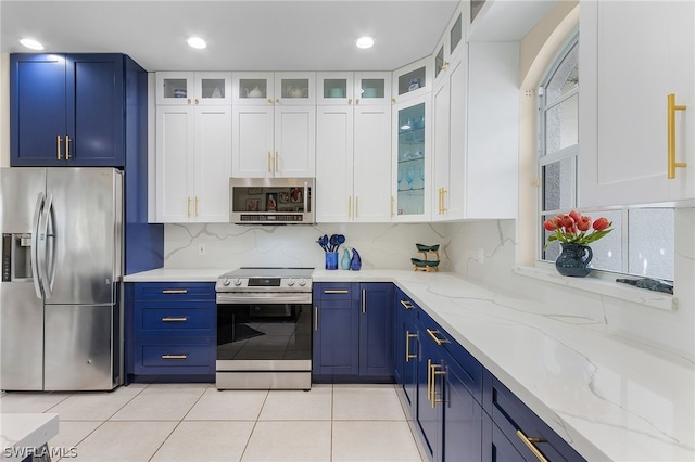 kitchen featuring appliances with stainless steel finishes, backsplash, blue cabinetry, light tile patterned floors, and white cabinetry