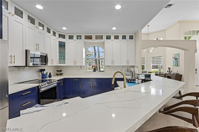 kitchen featuring a wealth of natural light, light stone counters, stainless steel appliances, and blue cabinets