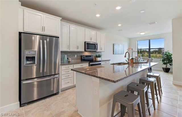 kitchen featuring sink, white cabinetry, appliances with stainless steel finishes, and an island with sink