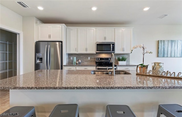 kitchen featuring stone counters, appliances with stainless steel finishes, white cabinets, and sink