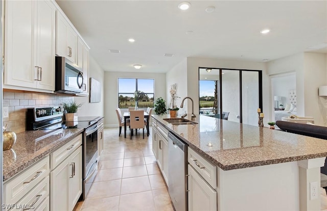 kitchen with stainless steel appliances, sink, white cabinetry, and an island with sink