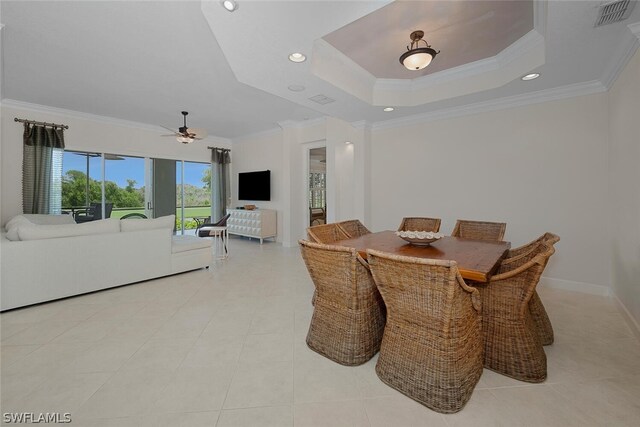 dining area featuring a raised ceiling, ornamental molding, light tile patterned floors, and ceiling fan