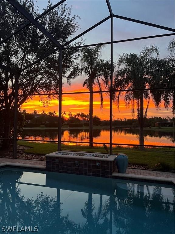 pool at dusk with a lanai and a water view