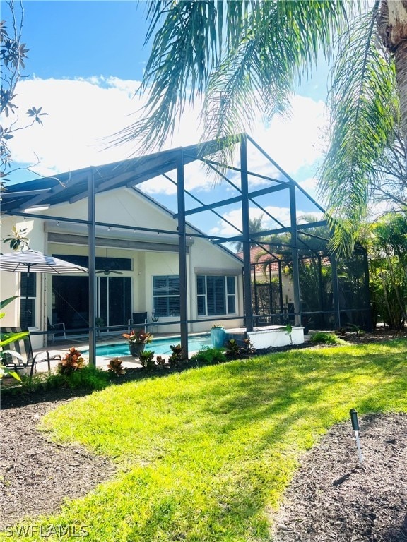 back of property with a yard and glass enclosure