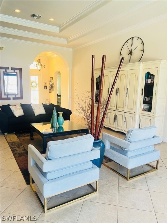 tiled living room with a raised ceiling, a notable chandelier, and ornamental molding