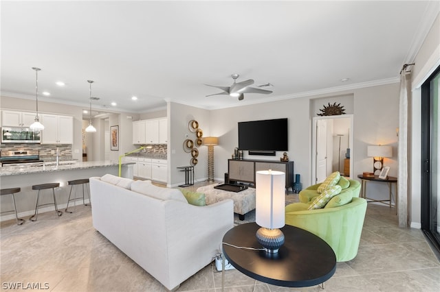 living room featuring ceiling fan, sink, and crown molding