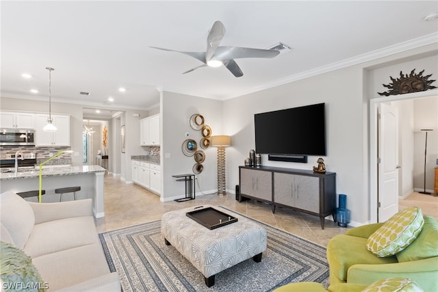 living room featuring ceiling fan, sink, and crown molding