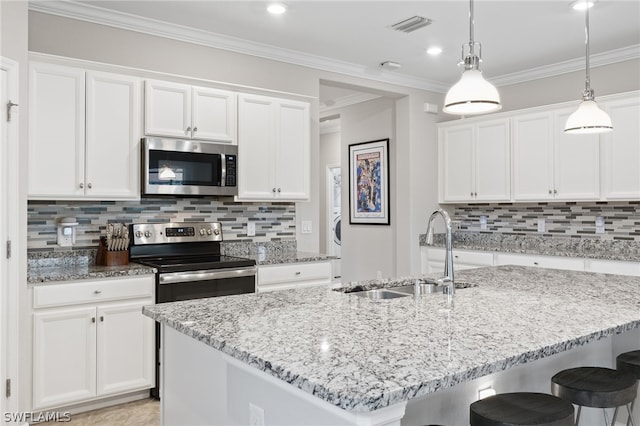 kitchen with appliances with stainless steel finishes, a kitchen island with sink, white cabinets, and sink