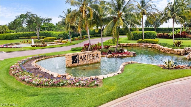 view of home's community with a lawn and a garden pond