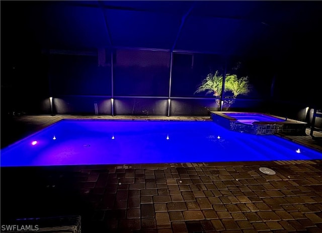 pool at twilight featuring an in ground hot tub