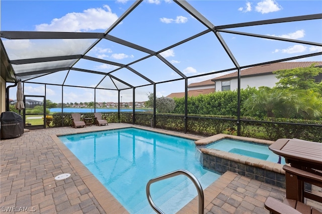 view of pool with a patio area, glass enclosure, a water view, and an in ground hot tub