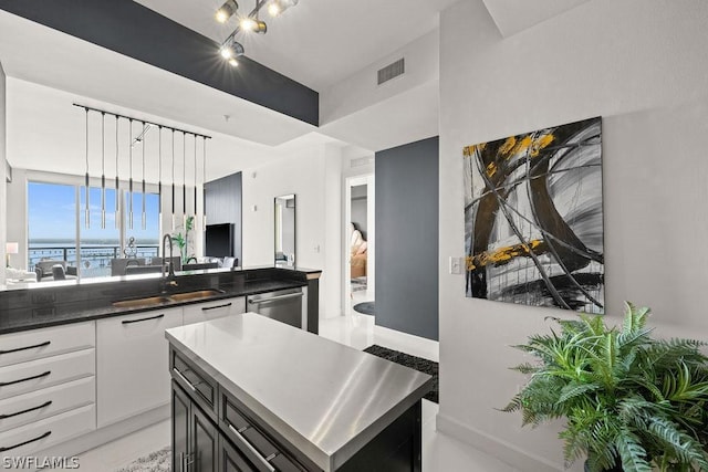 kitchen with rail lighting, visible vents, open floor plan, a sink, and dishwasher