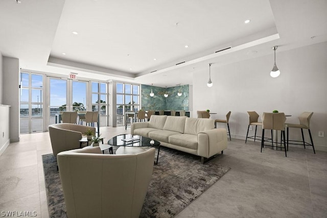 living area with recessed lighting, a raised ceiling, and baseboards