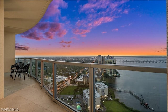 balcony at dusk with a water view and a city view