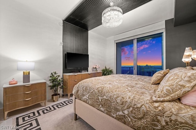 carpeted bedroom featuring access to exterior, vaulted ceiling, and an inviting chandelier