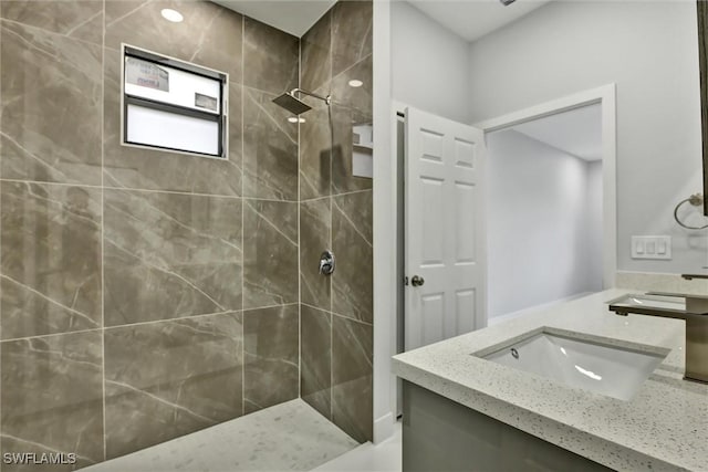 bathroom with tiled shower and vanity