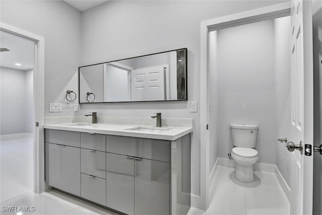 bathroom with double vanity, tile patterned floors, toilet, and a sink