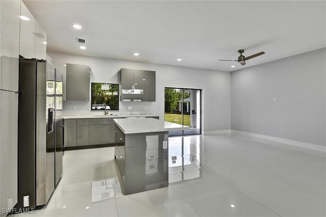 kitchen with gray cabinets, a sink, light countertops, modern cabinets, and stainless steel fridge