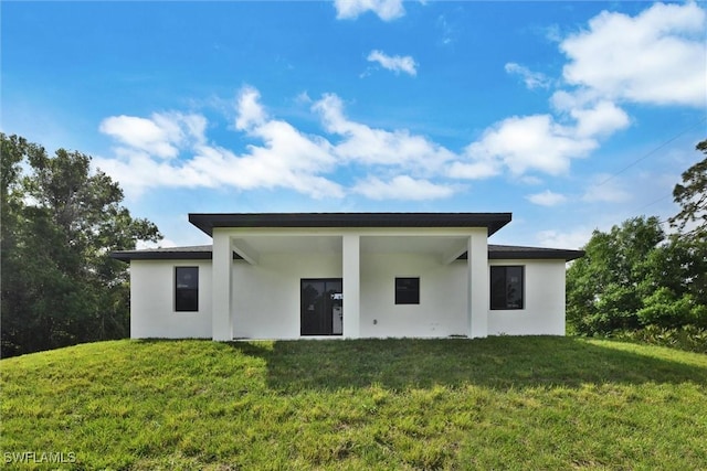 rear view of property with a yard and stucco siding