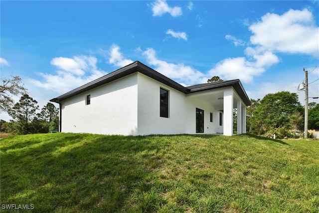 view of side of property featuring stucco siding and a yard