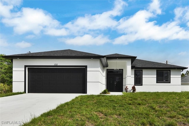 prairie-style home featuring a garage, driveway, a front lawn, and stucco siding