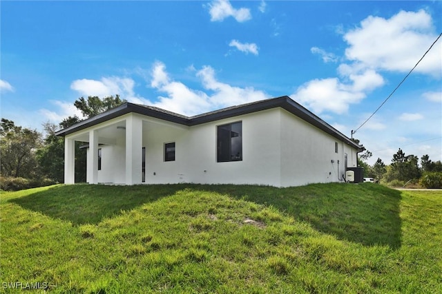 back of property featuring a lawn, central AC, and stucco siding