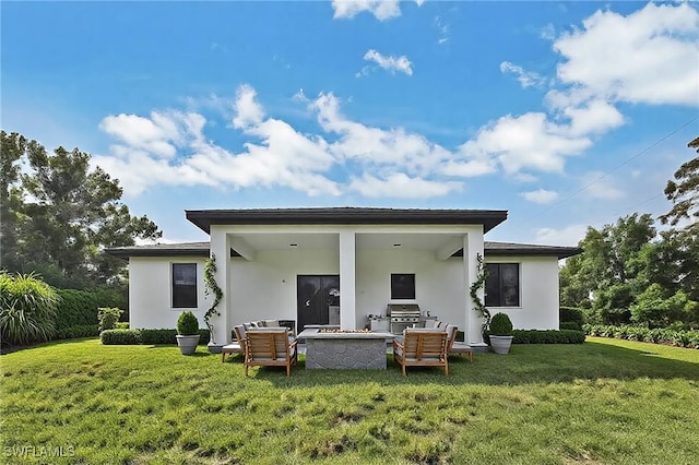 rear view of house featuring an outdoor living space with a fire pit, a lawn, and stucco siding