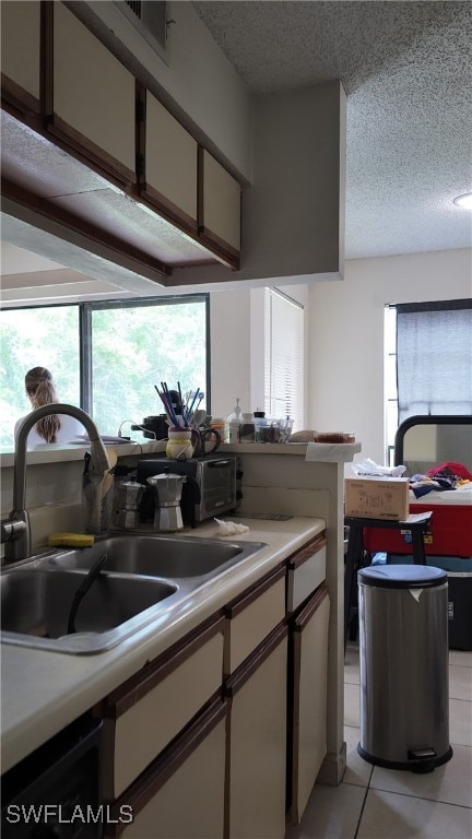 kitchen with sink, light tile patterned floors, a textured ceiling, and a wealth of natural light