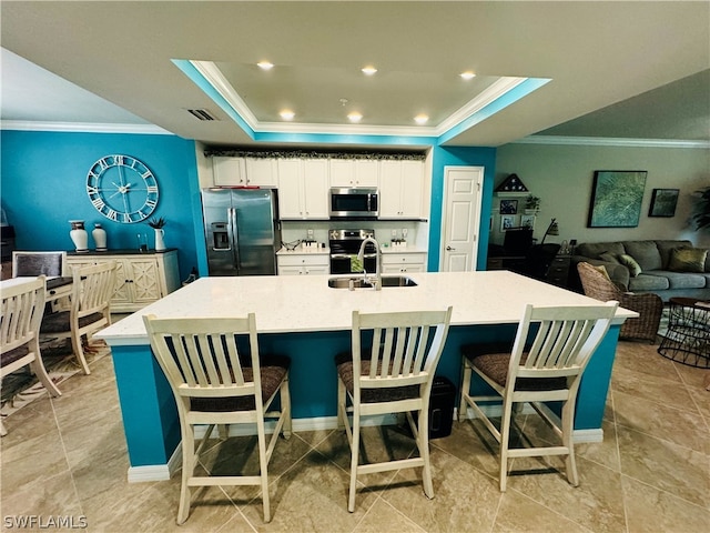 kitchen with a spacious island, a tray ceiling, stainless steel appliances, white cabinets, and a breakfast bar area