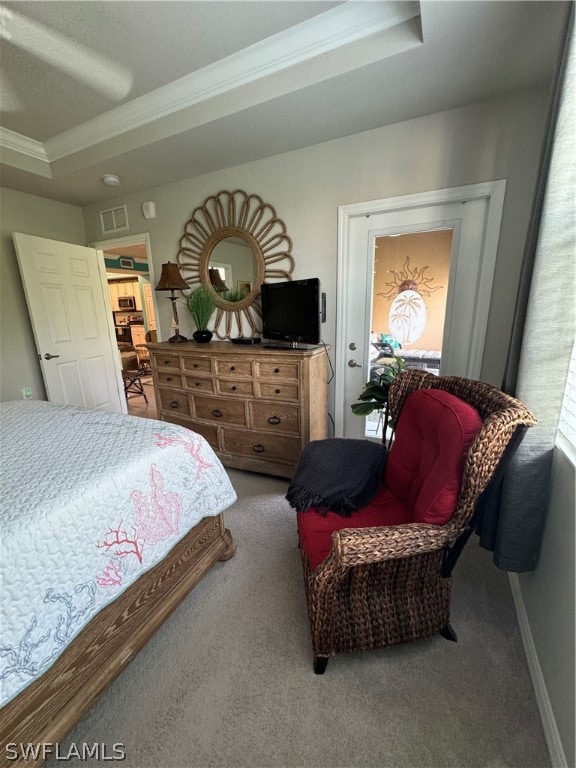 carpeted bedroom featuring a raised ceiling and ornamental molding