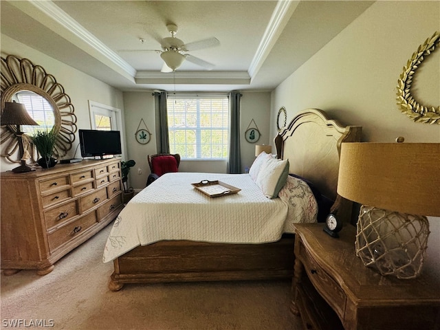 carpeted bedroom with ornamental molding, multiple windows, a tray ceiling, and ceiling fan