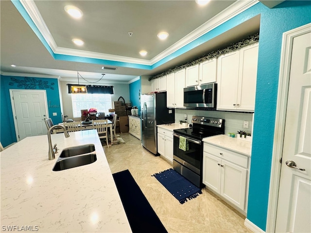 kitchen featuring stainless steel appliances, a tray ceiling, a sink, and white cabinetry