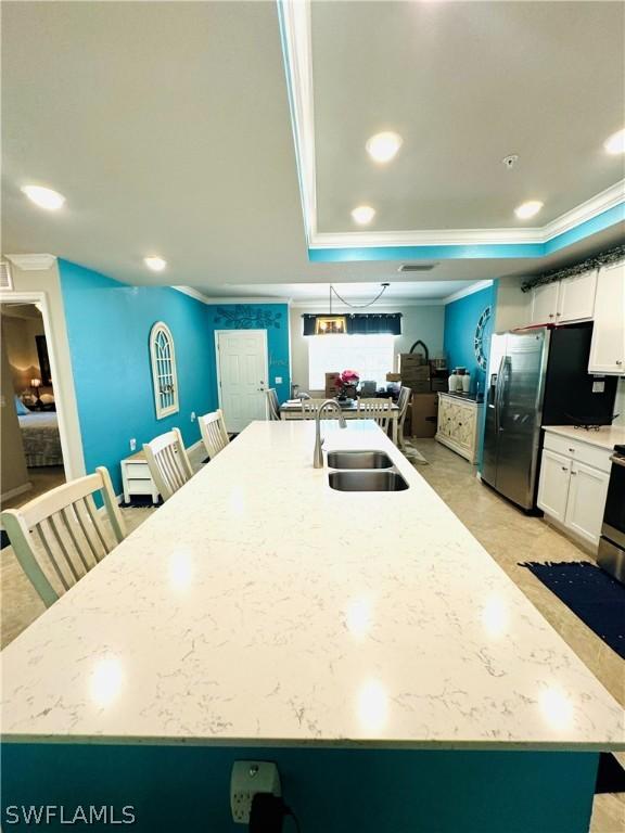 kitchen with white cabinetry, a kitchen island with sink, sink, and a breakfast bar area